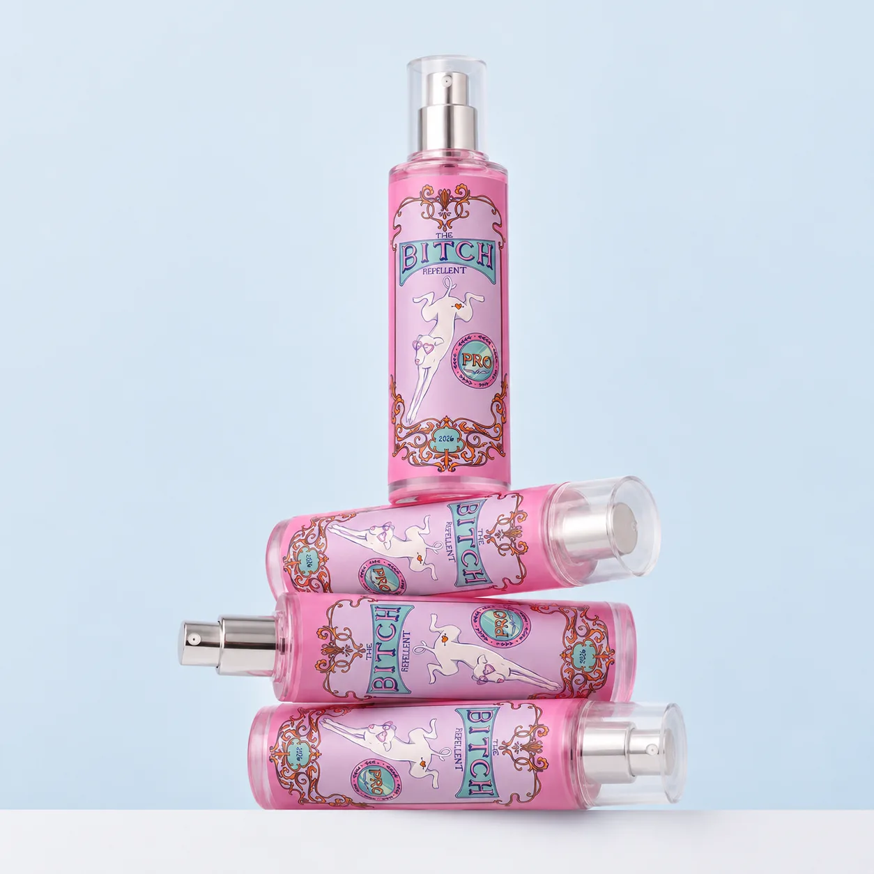Four Bitch Repellent spray bottles stacked, one standing upright on three lying on their sides, against a pale blue wall